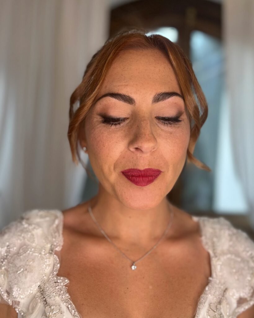 Maquillaje de novia con pecas con ahumado difuminado en tonos marrones mate. Maquillaje de novia con labio rojo.